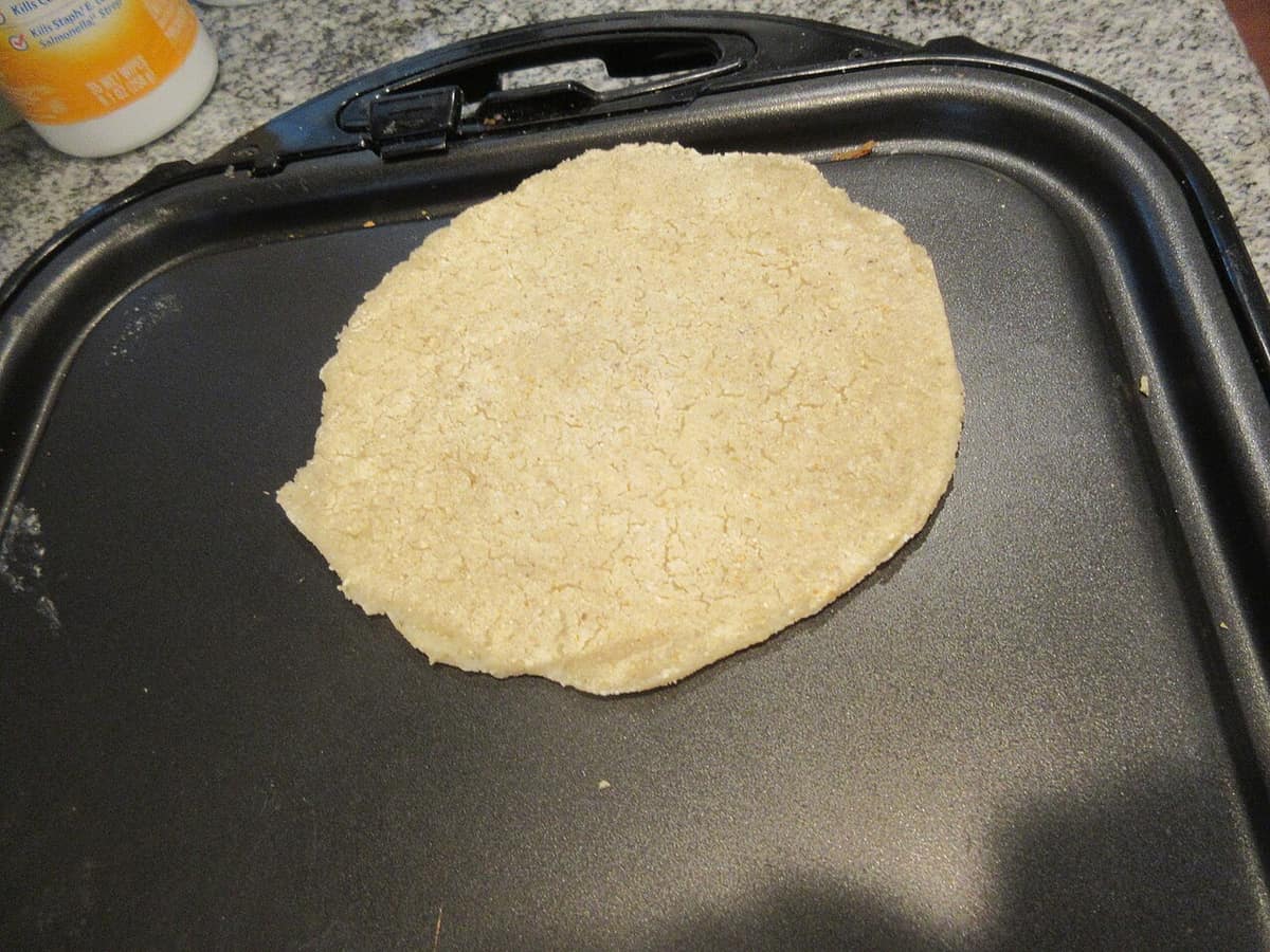 A tortilla cooking on an electric countertop griddle
