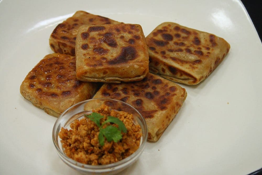 Stuffed flatbread cooking on a flat griddle surface